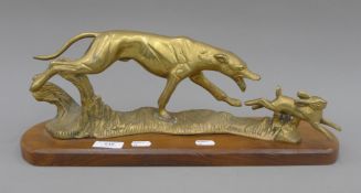 A brass model of a greyhound coursing a hare, on a polished wooden base. 45 cm long.