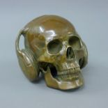 A bronze model of a skull and headphones. 15 cm high.