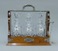 A silver plate mounted mahogany three bottle tantalus with Crown Staffordshire porcelain decanter