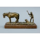 A bronze model of a farmer and his horse mounted on a wooden base. 20 cm long.