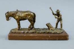 A bronze model of a farmer and his horse mounted on a wooden base. 20 cm long.
