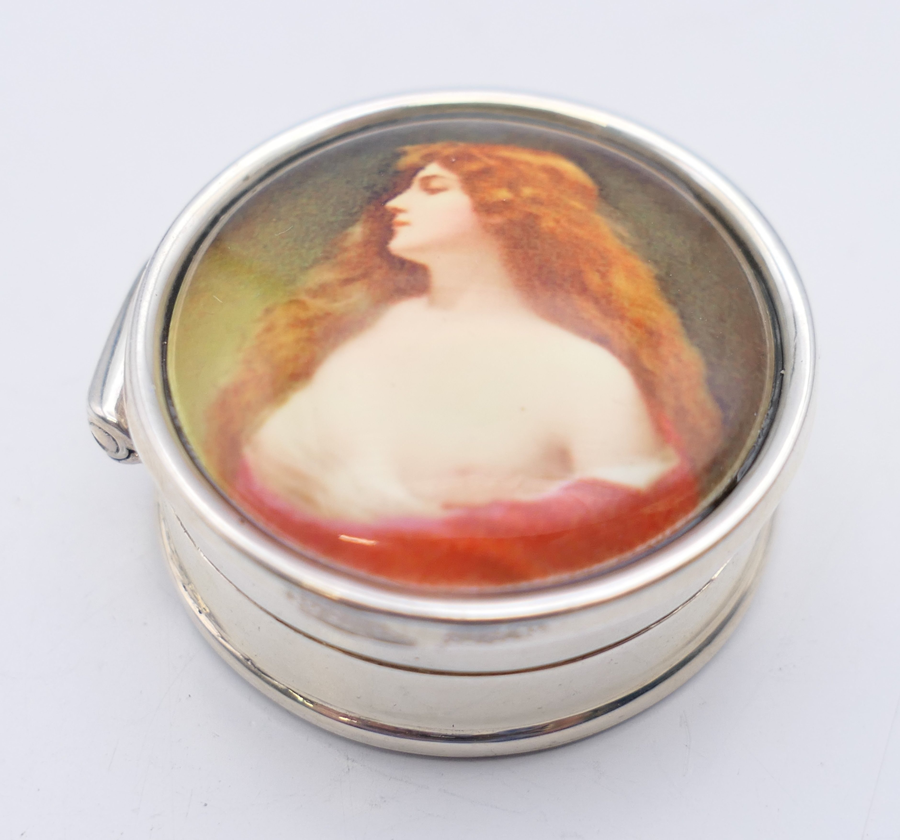 A pill box depicting a girl. 3 cm diameter.