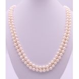 A double stranded well matched white pearl necklace with a 9 ct gold and garnet clasp. 54 cm long.