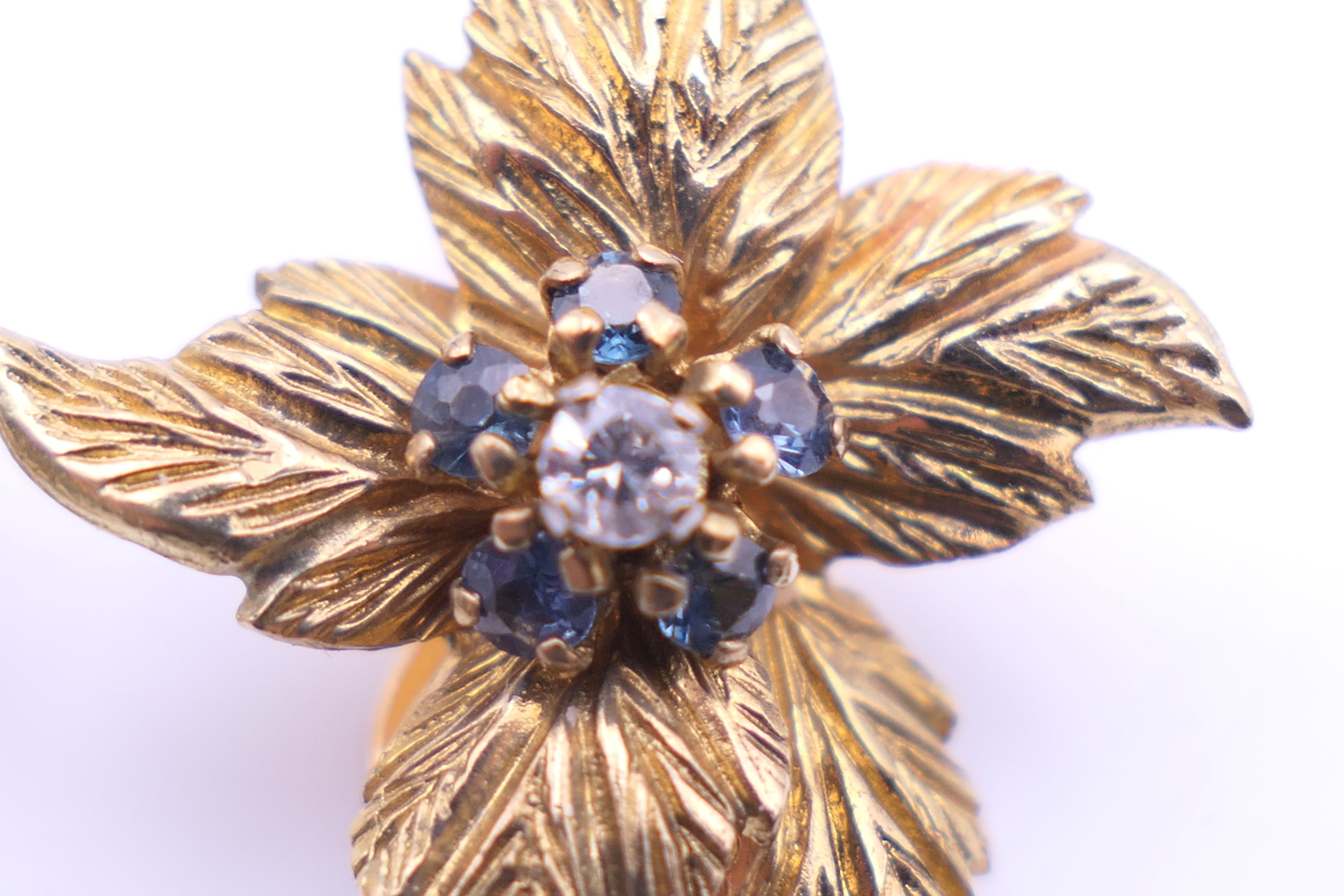 A Kutchinsky 18 ct gold diamond and sapphire set matching brooch and clip earrings of floral form. - Image 9 of 11