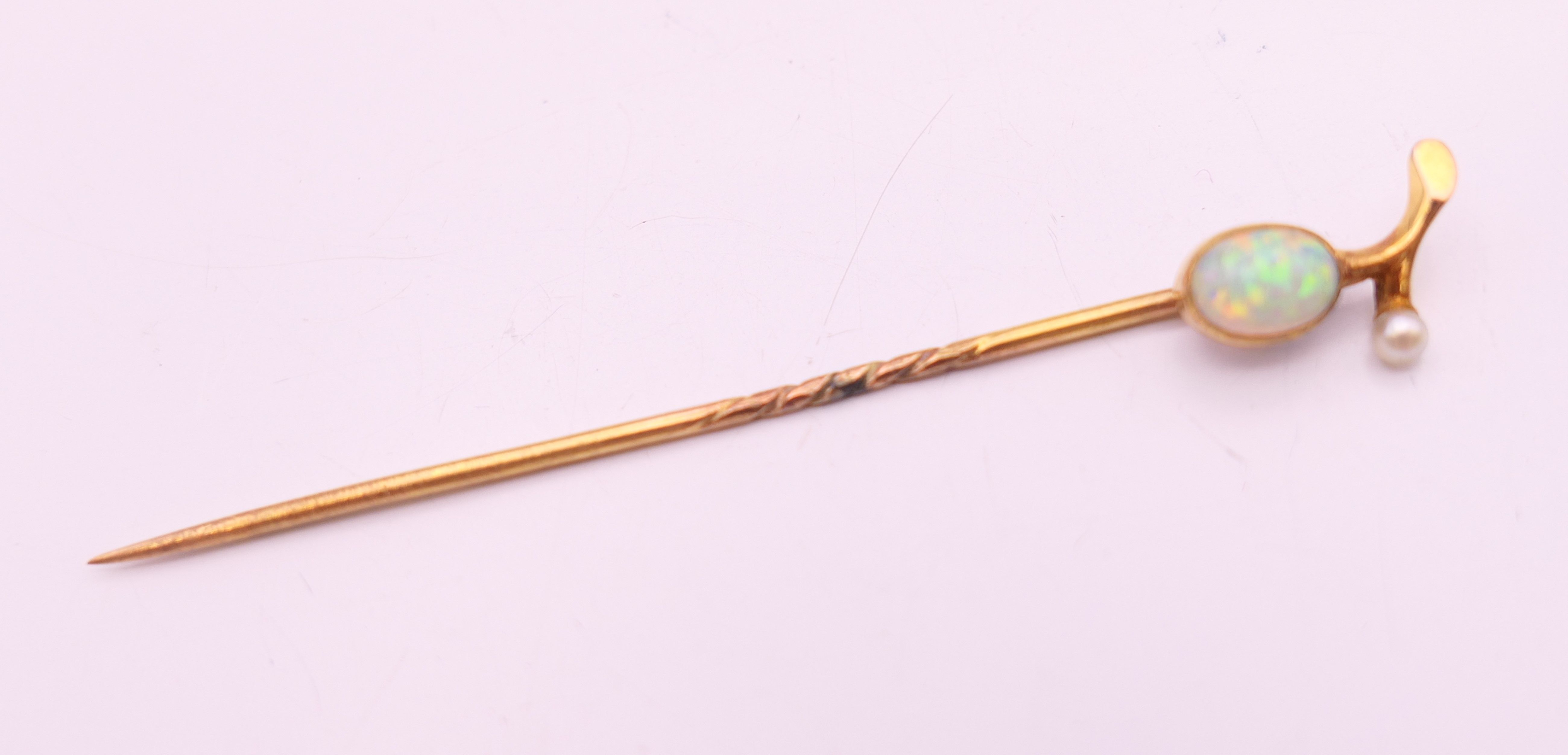 An unmarked 9 ct gold opal and pearl stick pin. 6 cm long. 1.2 grammes total weight.