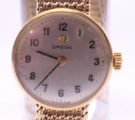 An Omega lady's 9 ct gold wristwatch. 2 cm diameter. 18.9 grammes total weight.