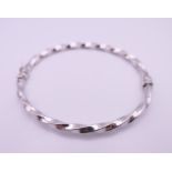 A 9 ct white gold bangle form bracelet. 6 cm internal diameter. 4.8 grammes total weight.