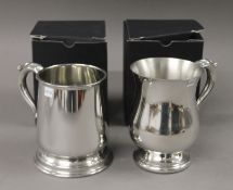 Two boxed pewter tankards. Each 13 cms high.