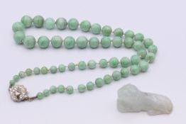 A jade bead necklace and a jade tiger form pendant. Bead necklace 42 cm long, pendant 3.5 cm long.