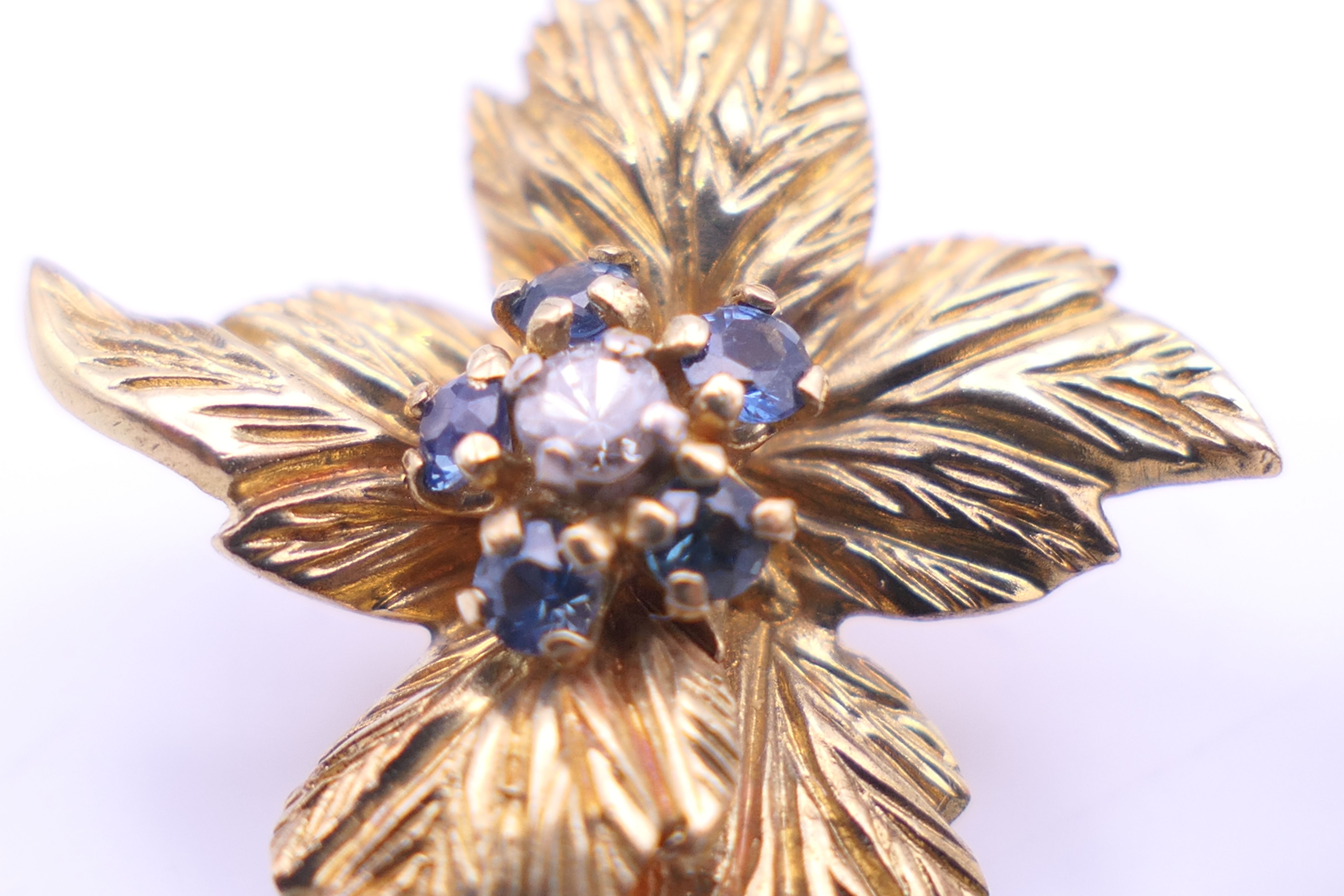 A Kutchinsky 18 ct gold diamond and sapphire set matching brooch and clip earrings of floral form. - Image 8 of 11