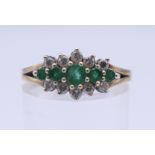 A 9 ct gold diamond and emerald ring. Ring size P. 2.7 grammes total weight.