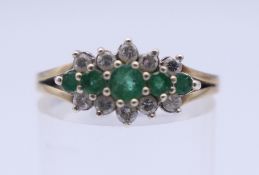 A 9 ct gold diamond and emerald ring. Ring size P. 2.7 grammes total weight.