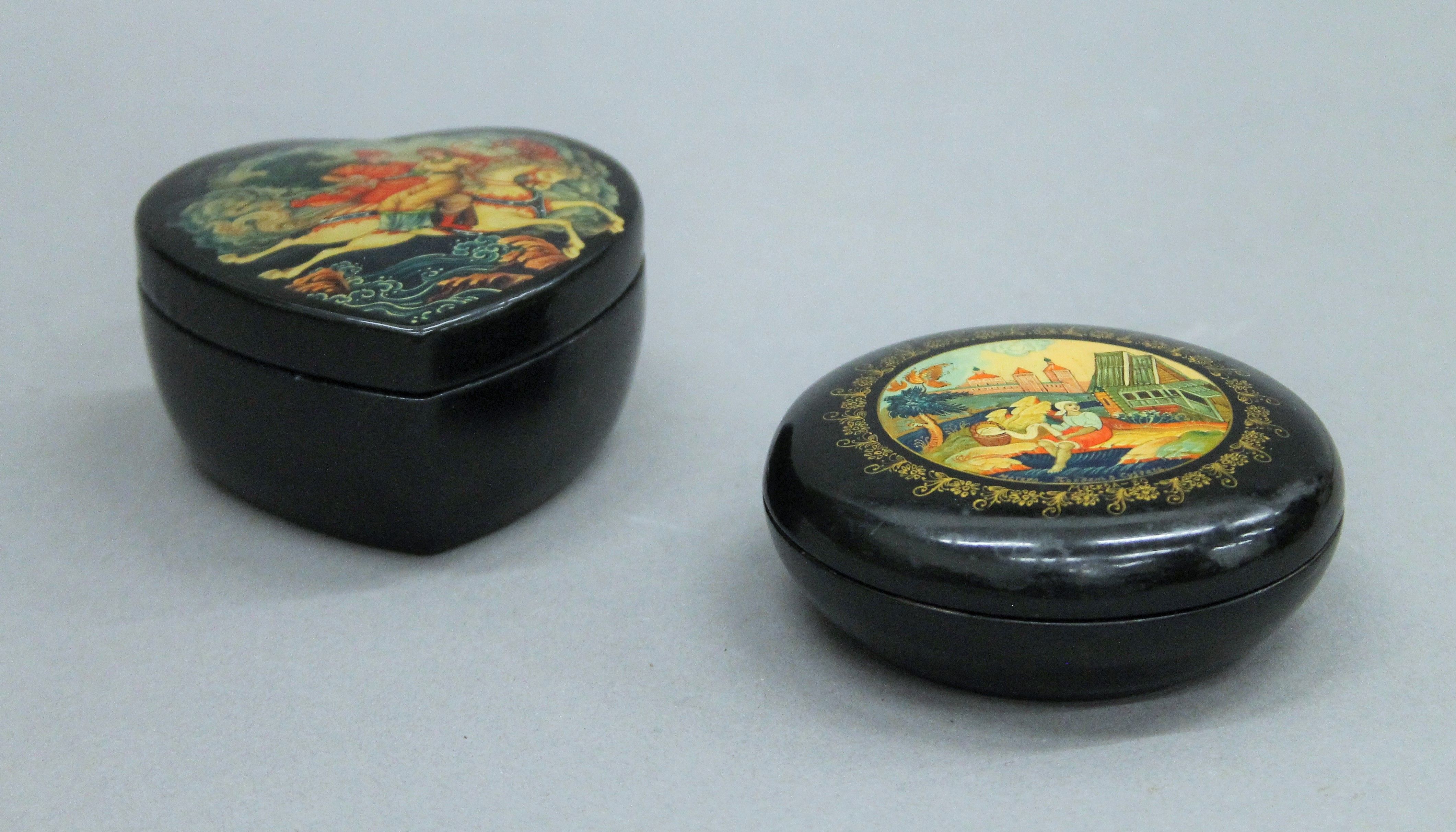 Two Russian black lacquered trinket boxes. The largest 9 cm diameter.