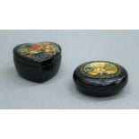 Two Russian black lacquered trinket boxes. The largest 9 cm diameter.