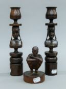 A pair of carved wooden candlesticks and a carved wooden figure. The former each 28 cm high.
