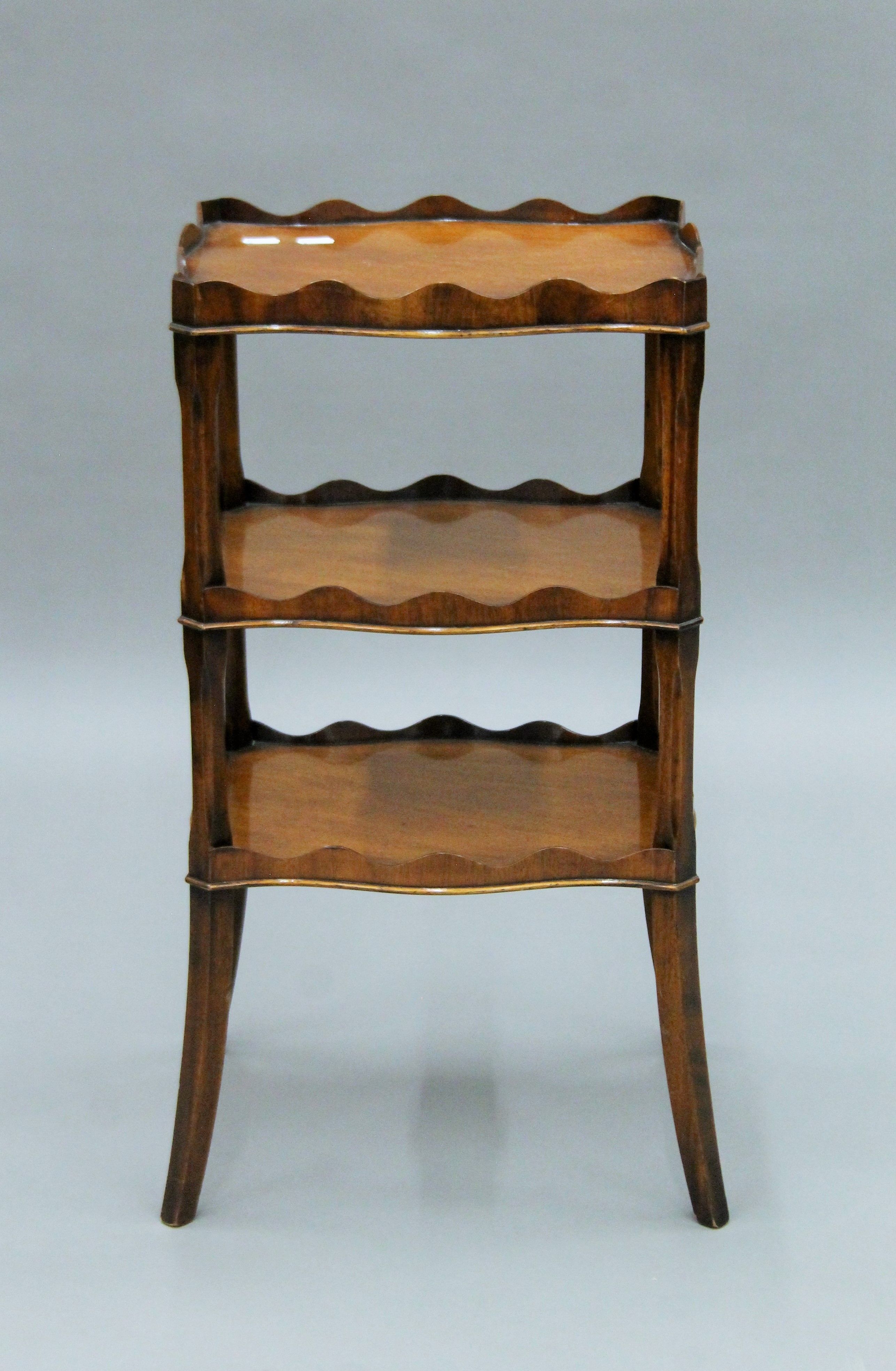 A three-tier mahogany Reprodux side table. 67.5 cm high.