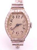 A 1920s ladies wristwatch with diamond set bezel on a 9 ct white gold 1960s bracelet. 1.75 cm wide.