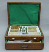 A Walker & Hall oak cutlery canteen containing an associated set of gold plated cutlery.