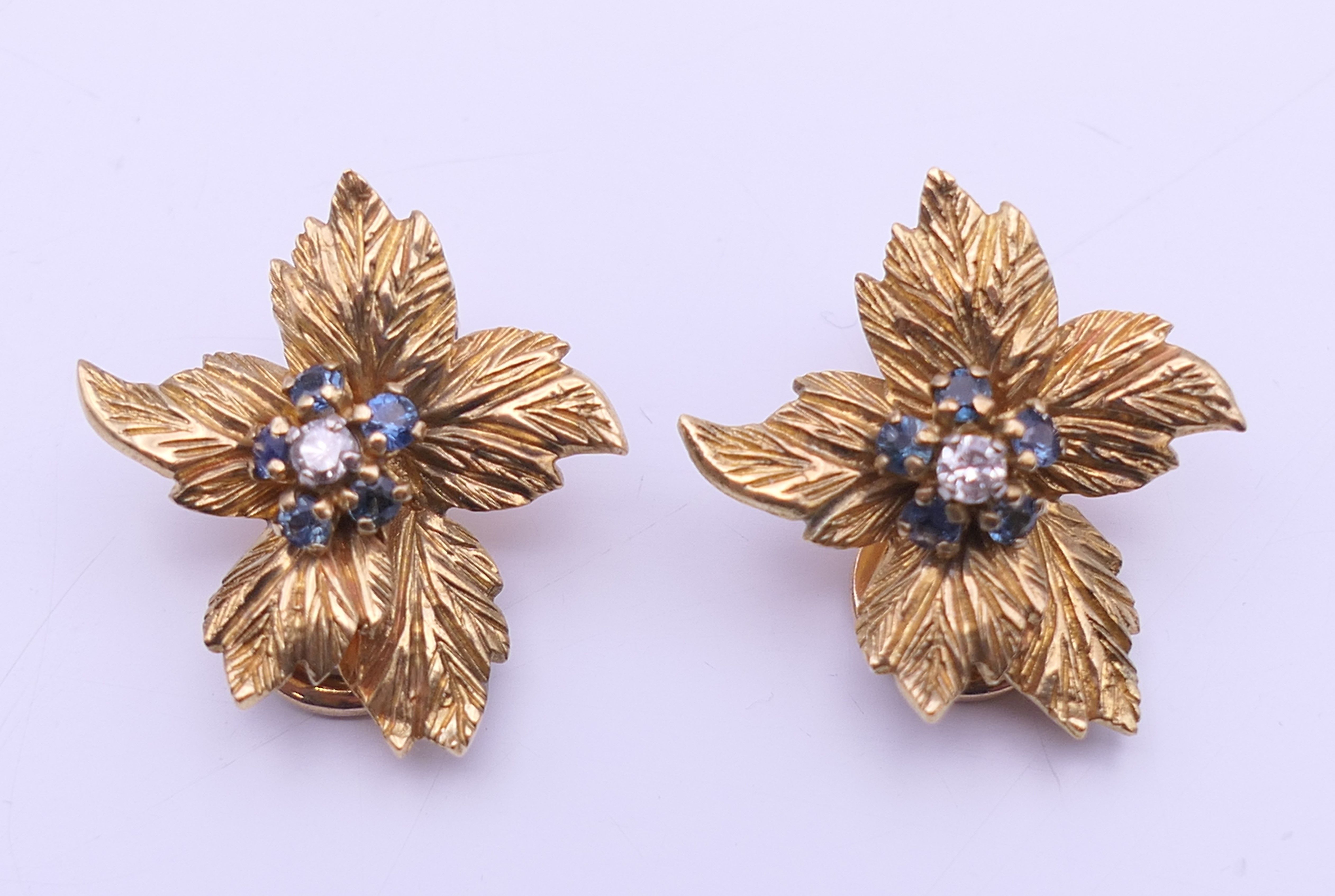 A Kutchinsky 18 ct gold diamond and sapphire set matching brooch and clip earrings of floral form. - Image 7 of 11