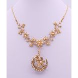 An unmarked gold seed pearl set necklace of scrolling floral form and detachable pendant formed as