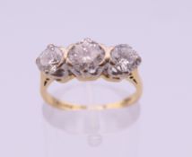 An 18 ct gold three stone diamond ring. Approximate diamond weight 1.7 carats. Ring size L. 3.