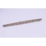 An unmarked white gold diamond bar brooch. Approximate diamond weight 2 carats. 8 cm long. 6.