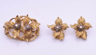 A Kutchinsky 18 ct gold diamond and sapphire set matching brooch and clip earrings of floral form.
