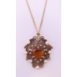 A 9 ct gold citrine and seed pearl pendant on a 9 ct gold chain.