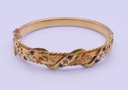 A 9 ct gold diamond and ruby bangle form bracelet. 6 cm internal diameter. 11.