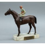 A painted spelter model of a racehorse with jockey up, mounted on a marble base,