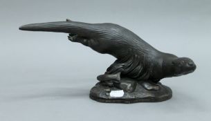 A cast resin 'Heredities' figure of an otter at swim, signed 'Tom Mackie '81' to base. 31 cm long.