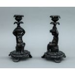 A pair of cast bronze candlesticks formed as putto. 21 cm high.