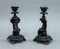 A pair of cast bronze candlesticks formed as putto. 21 cm high.