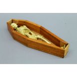 A model of a skeleton in a coffin. The coffin 30.5 cm long.