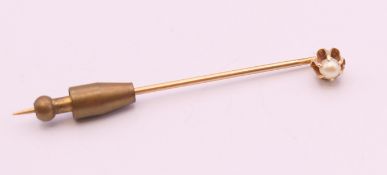 An unmarked 9 ct gold stick pin mounted with a single pearl. 5.5 cm long.
