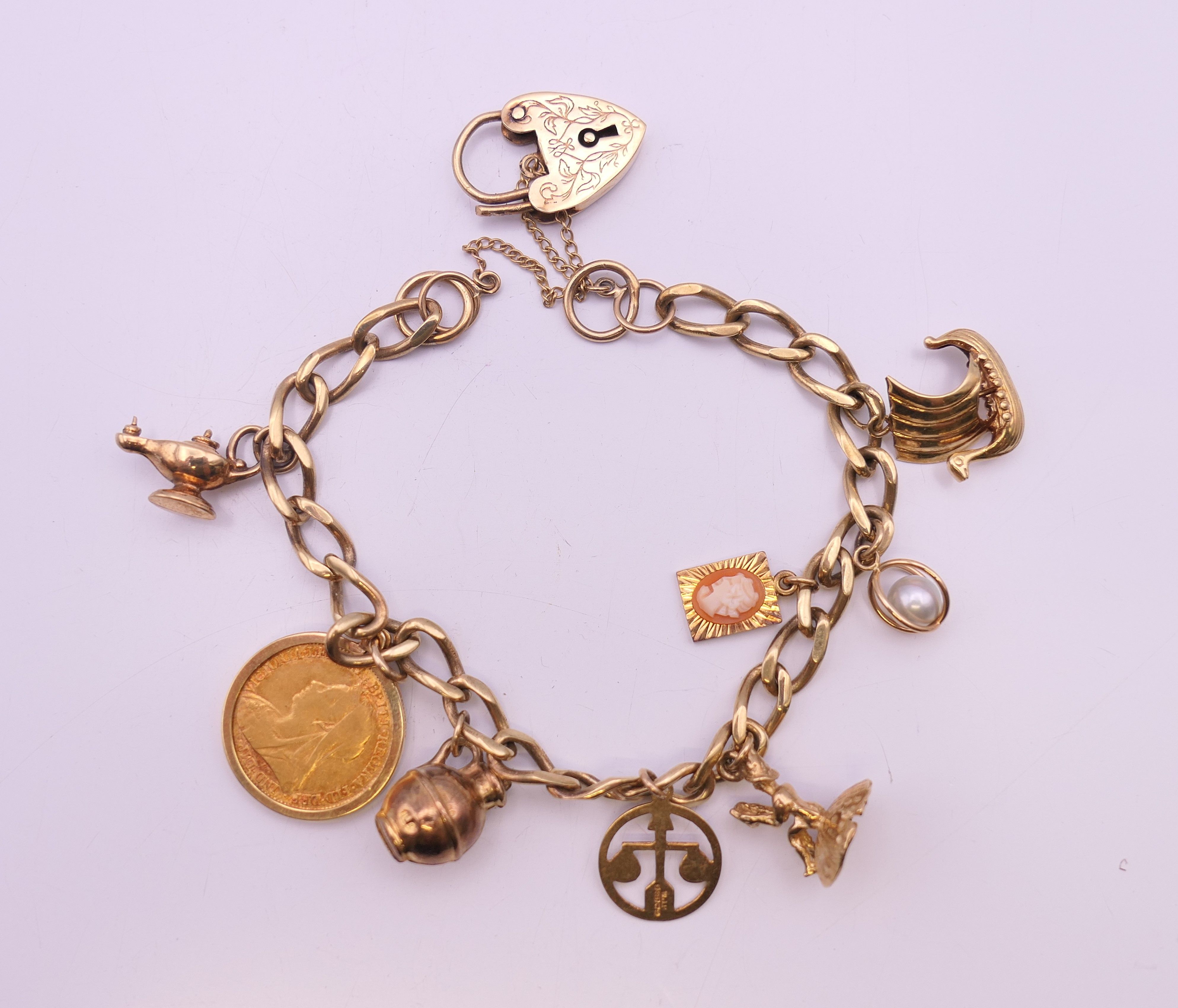 A 9 ct gold charm bracelet, set with various charms and an 1894 half sovereign. 25.