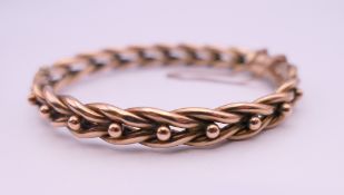 A 9 ct gold bangle form bracelet. 5.75 cm internal diameter. 10.9 grammes.