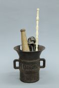 A cast iron mortar, a skull form nut cracker, a pestle and a baton. The former 15 cm high.