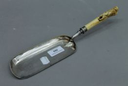 A silver plated crumb scoop with stag antler handle carved with monkeys. 33 cm long.