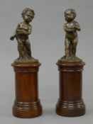 A pair of bronze putto on wooden plinth bases. Each approximately 29 cm high.
