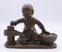A bronze model of a boy cooking. 7.5 cm wide.