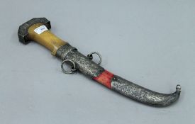 An antique jambiya, the handle possibly rhino horn and with unmarked white metal mounted scabbard,