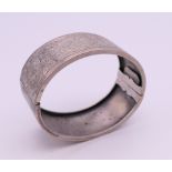 An engraved silver bangle form bracelet. 6.5 cm wide. 28.6 grammes.