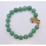 A Chinese jade bead bracelet with 14 K gold clasp. 20 cm long.