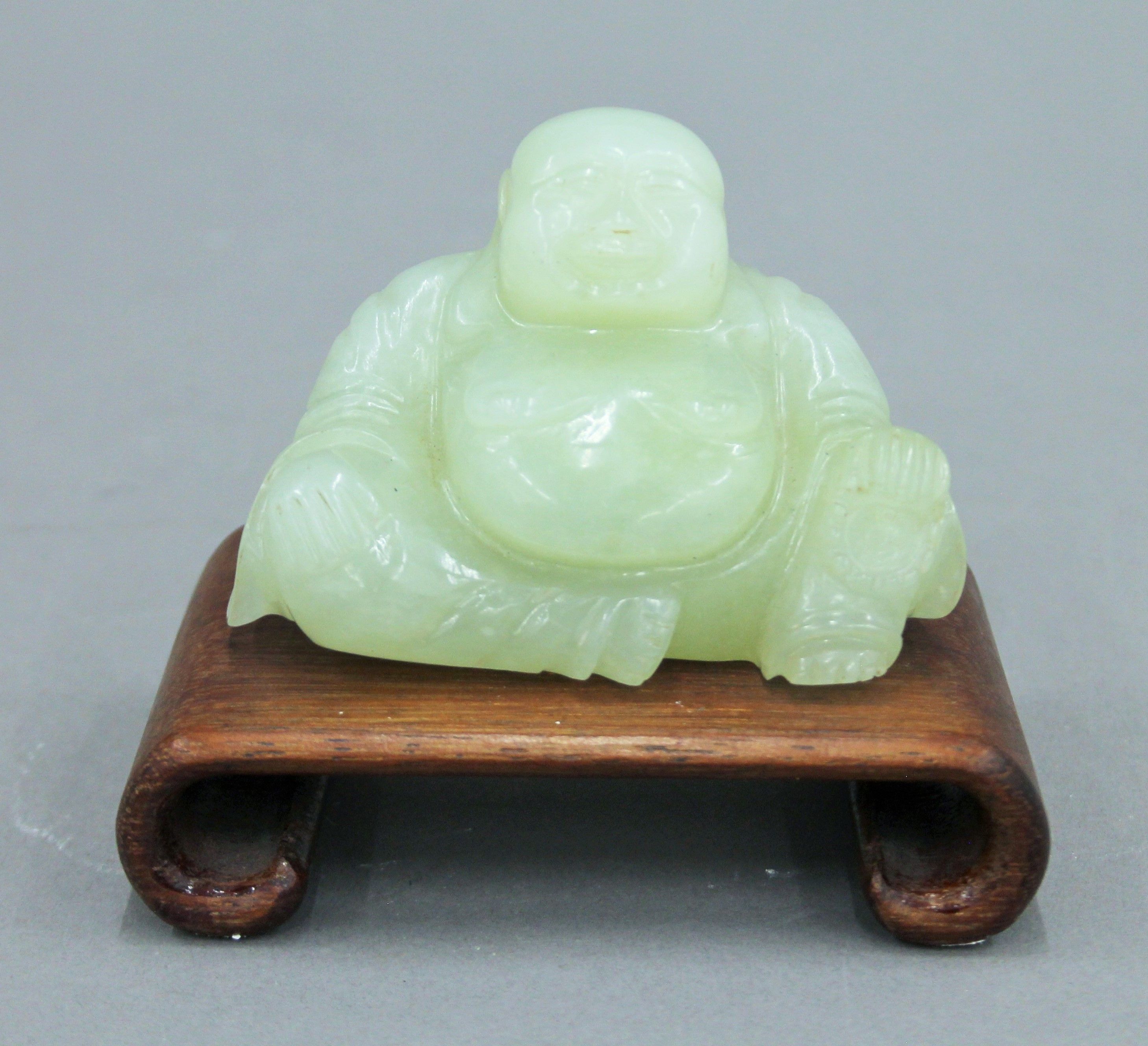 A Chinese model of Buddha on a wooden stand. 10 cm high overall.