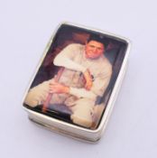 A silver pill box depicting a baseball player. 2.5 cm wide.