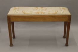 An early 20th century tapestry covered duet piano stool. 90 cm long.