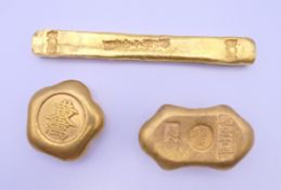 Three gold coloured scroll weights. The largest 12 cm long.