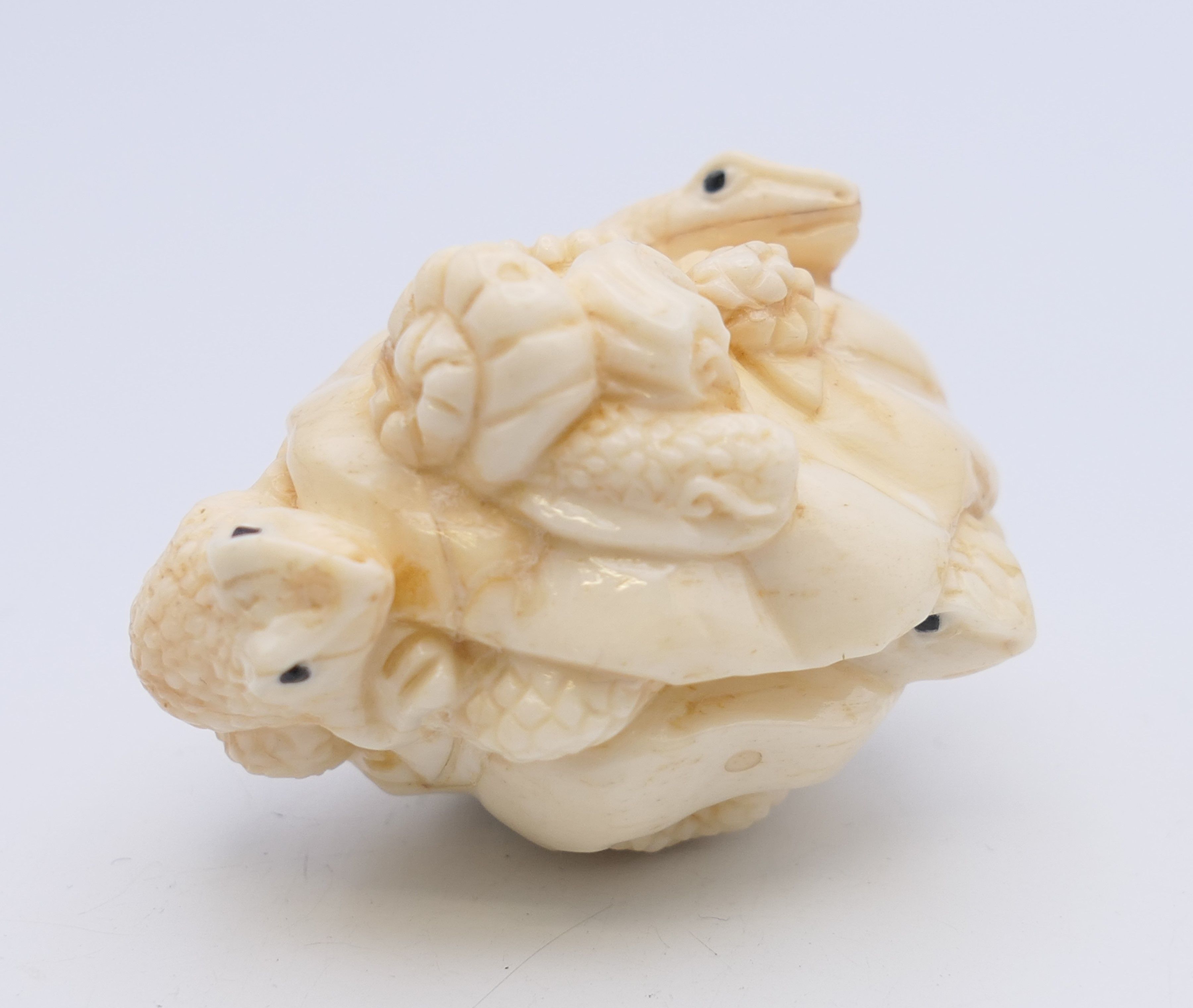 A bone carving of frogs. 5 cm long.