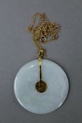 A pale green/near white jade bi disc pendant with 14 K gold adornments,